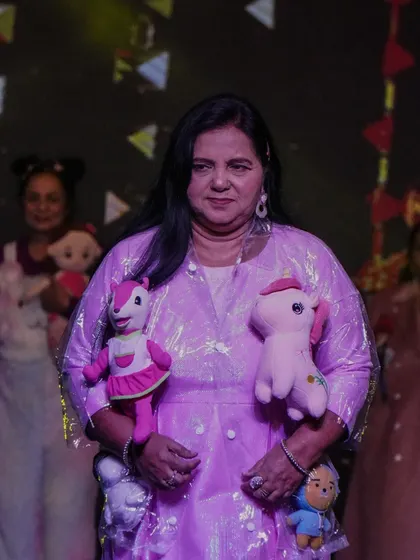 A senior performer on stage with plush toys as props, part of a fun and whimsical act.