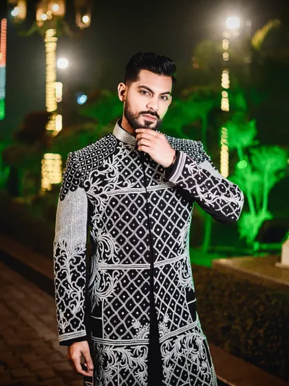 A confident pose in our black and ivory embroidered jacket. The contrast between the dark fabric and the light embroidery makes this a visually striking piece for any special occasion.