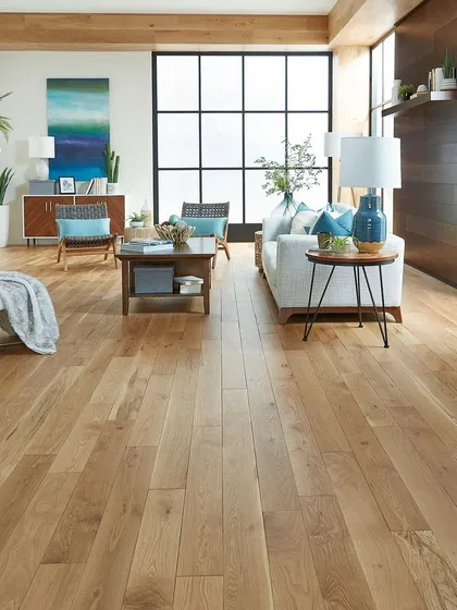 In this bright and open living room, the wide-plank, light-colored hardwood floor enhances the sense of space and light. It pairs beautifully with the dark-framed windows and wooden accent wall for a sophisticated, transitional look.