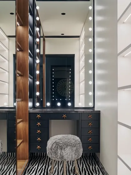 A glamorous vanity with a large mirror and bright makeup lights. The zebra-print rug and fluffy stool add a fun, playful touch to this chic dressing area.