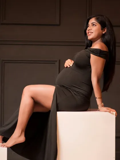Sometimes, simplicity is the most powerful. This classic, elegant portrait in a simple black dress highlights the beautiful silhouette of motherhood against a dark, moody backdrop.