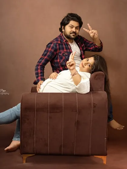 A fun and casual maternity portrait of a couple. They strike a playful pose on a sofa, showing that maternity shoots can be relaxed and reflect your personality.