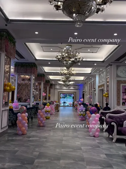 A wide view of the banquet hall decorated for a grand first birthday party, with balloon pillars lining the walkway.