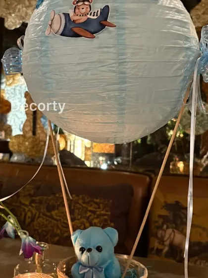 A detailed look at the hot air balloon table centerpiece, with a paper lantern balloon and a cute teddy bear pilot.