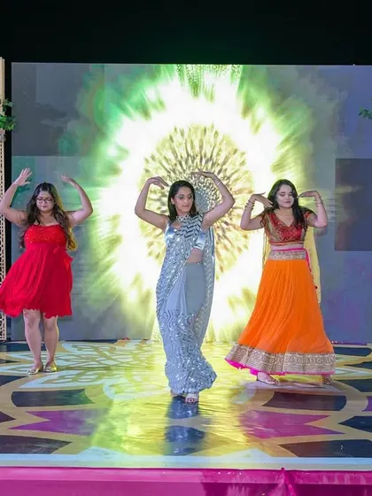 A vibrant performance by the bridesmaids on the Sangeet stage, which features a unique patterned dance floor and elegant floral archways.
