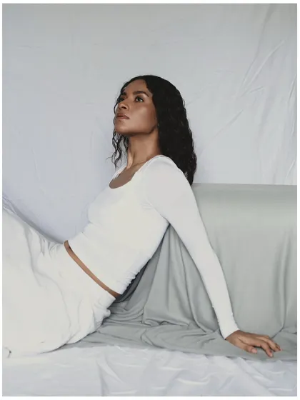 This is an example of a minimal, clean studio portrait. The all-white styling and simple draped background keep the focus entirely on the model. The lighting is soft and diffused, creating a serene and ethereal mood.