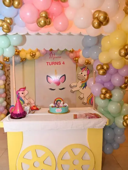 A close-up of the unicorn-themed cake table, complete with a custom cart, pastel balloon decor, and a beautiful cake. Every detail is designed to be picture-perfect.