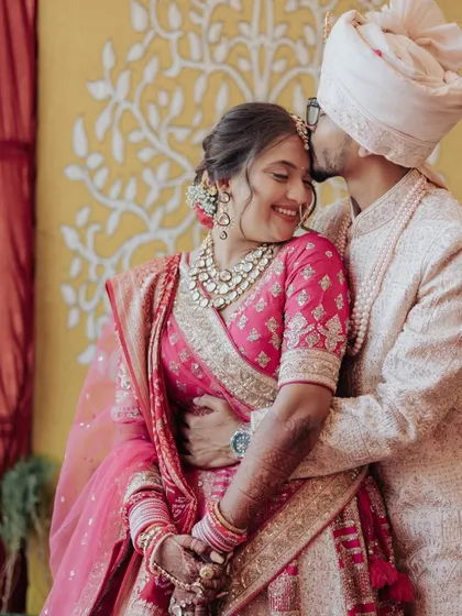 A tender moment as the groom, Harsh, kisses his bride Shreya on the forehead. A classic expression of love and care.