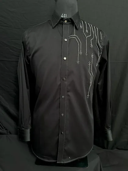 This black shirt features abstract, circuit-board-like embroidery in silver thread on one shoulder. It's a futuristic and edgy design for the modern man.