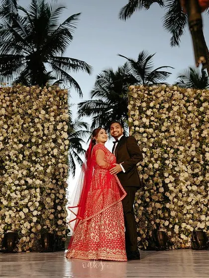 Aysha and Farhan looking regal and happy at their beach reception. The bride's red lehenga was a stunning contrast against the white floral walls.