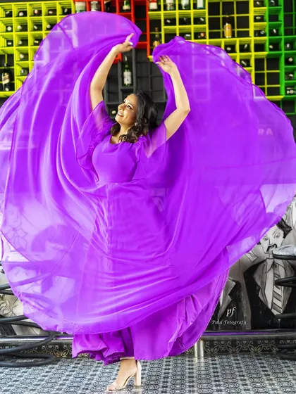 A joyful shot of a model dancing in the purple gown, with the fabric creating a stunning circular shape.