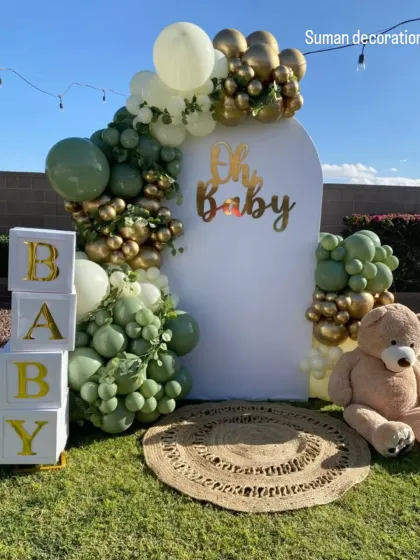 An outdoor baby shower with a rustic, boho theme. I used a white arched backdrop, a balloon garland in sage green and gold, 'BABY' blocks, and a teddy bear prop.