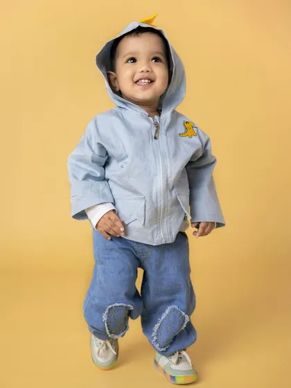 A joyful toddler in a blue hooded jacket and jeans walks with a big smile. His happy expression and cute outfit make for a heartwarming baby portrait.
