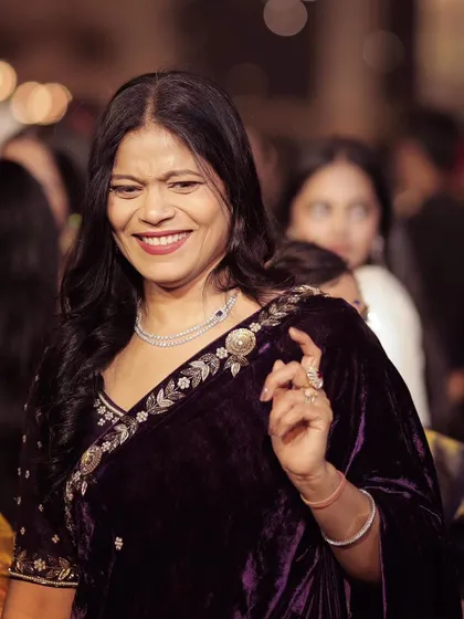 A candid moment showing the joy of the occasion. The detailed hand embroidery on the velvet blouse, featuring pearls and dabka, is clearly visible here.