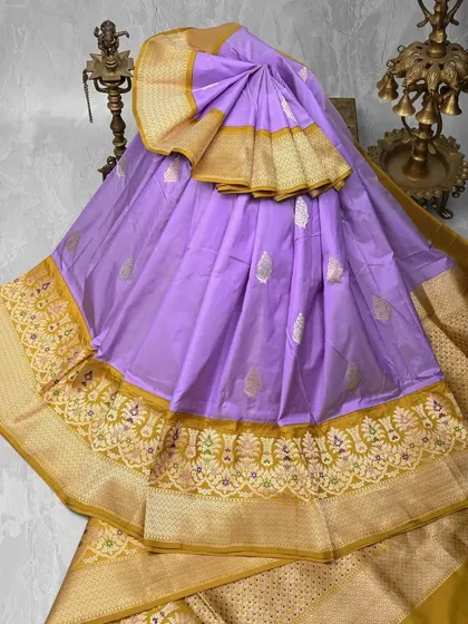 A lovely lavender silk saree with an intricately embroidered gold border. The soft pastel shade makes it a unique and elegant choice for special occasions.