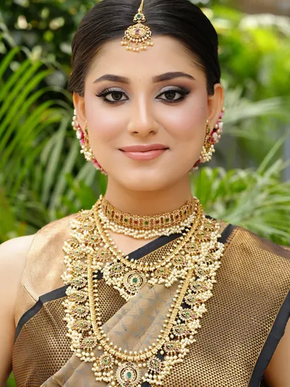 A full view of the South Indian bridal makeup. The skin is kept fresh and radiant, with a neutral lip color to balance the intricate gold jewelry and saree.