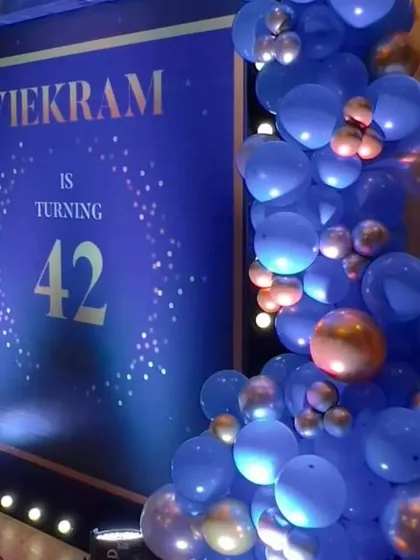 An elegant and modern setup for a 42nd birthday party. The deep blue and gold theme, complete with a custom digital backdrop and a stylish balloon arch, is perfect for a sophisticated celebration.