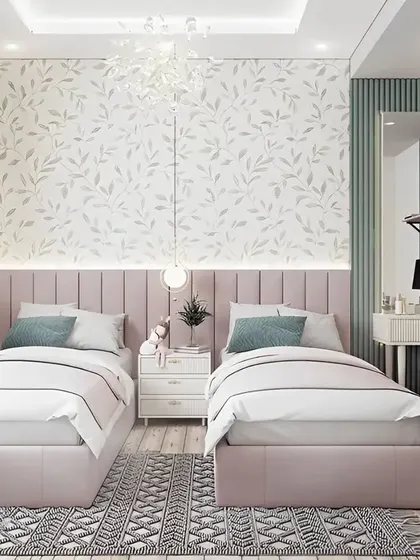 An elegant shared bedroom for two girls, featuring matching pink upholstered beds and a shared dressing table. The soft floral wallpaper and fluted green accent wall create a chic and serene environment.