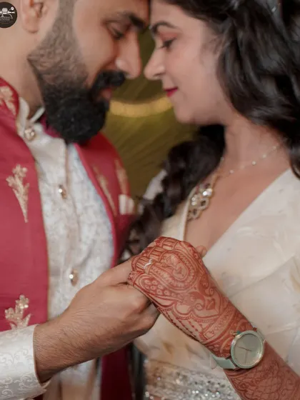 A detailed close-up shot focusing on the couple's hands, showcasing the intricate henna design on the bride's hand. This type of photo captures the small, meaningful details of the wedding day.
