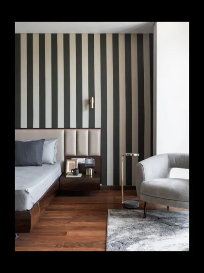 A closer look at the bedroom reveals how we layer textures and materials. The combination of a leather-paneled headboard, a bold wallpaper, and a sleek side table creates a composition that is both visually rich and functionally sound, perfect for a restful escape.