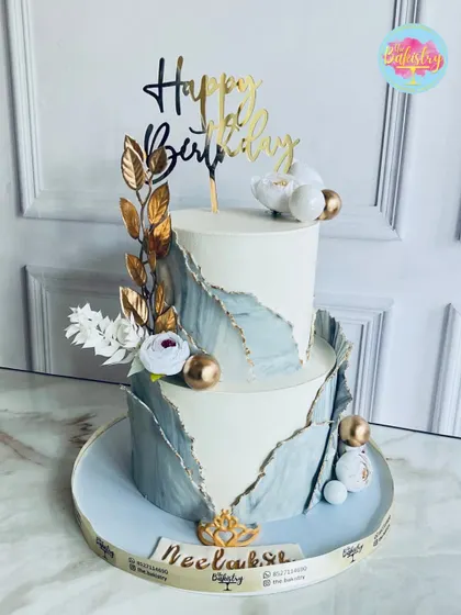 Indulge in pure luxury with this two-tiered cake, fit for royalty. The design features a beautiful fault line effect in grey and white, accented with gold leaf and spheres.