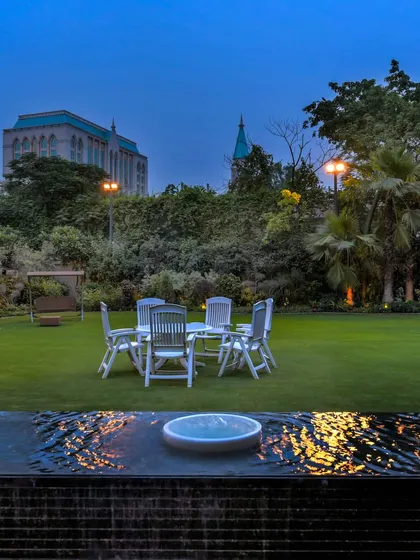 An elegant water feature serves as the tranquil foreground to a lush residential lawn. The gentle bubbling fountains add soothing sound and movement, perfectly complementing the serene evening ambiance and creating an ideal space for relaxation.