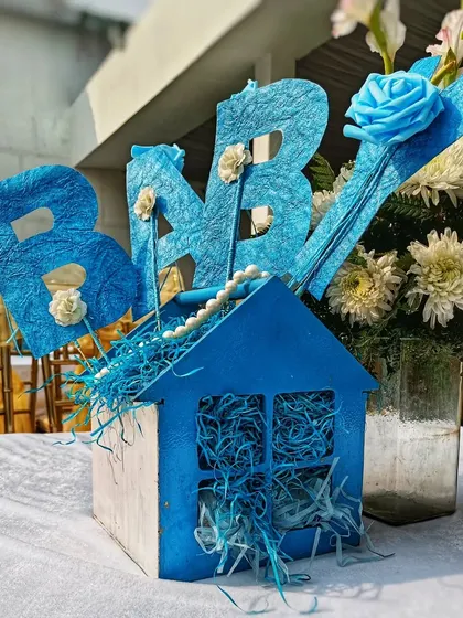 A handmade centerpiece for a baby shower. This little blue house with "BABY" letters is a charming and personal touch for the gift table or guest tables.