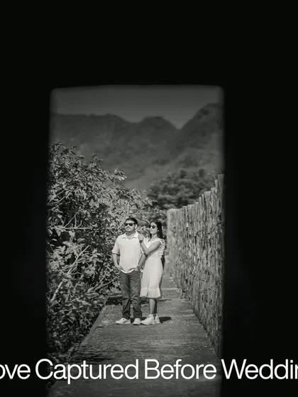 A moody, black and white shot framed by a dark doorway, creating a sense of intimacy and focusing on the couple against a natural, mountainous backdrop.