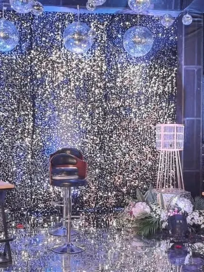 For a modern sangeet or cocktail night, I can create a high-energy atmosphere like this one. The entire space, including the walls, ceiling, and floor, is covered in silver sequins and complemented by hanging disco balls.