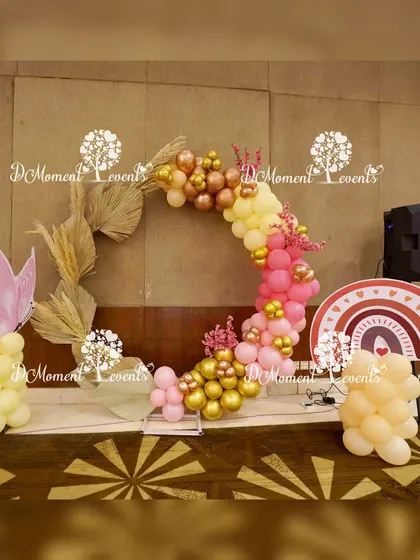 A modern, deconstructed circular arch with boho elements like dried palm leaves and a mix of gold and pink balloons.