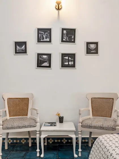 A cozy seating arrangement with classic, colonial-style chairs and a gallery wall of black and white architectural photos. The decor is timeless, elegant, and tells a story of place and history.