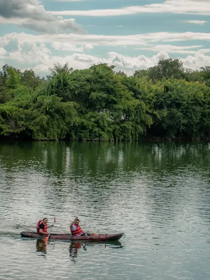 A couple enjoys a peaceful kayaking session, paddling together against a backdrop of beautiful trees.