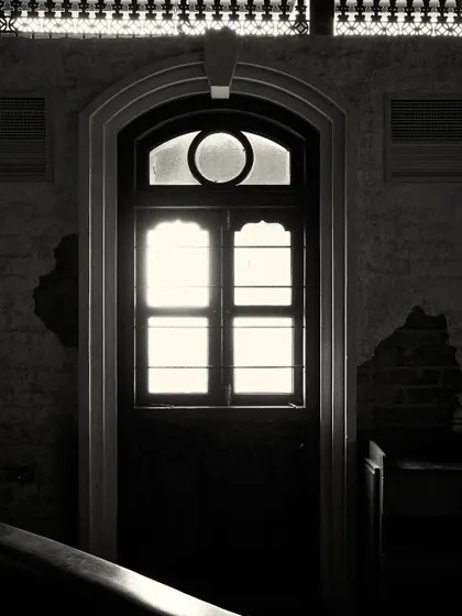 An arched doorway with a transom window, backlit to create a strong silhouette. This architectural detail is repeated throughout the space.