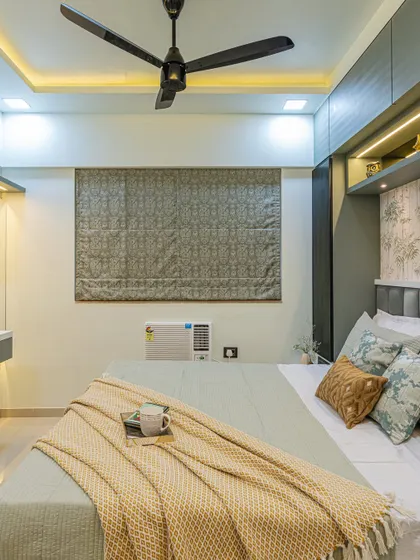 This view shows the balance of the room, with the cozy bed, functional window blinds, and the sleek fan. Every element is chosen to contribute to a comfortable and stylish whole.