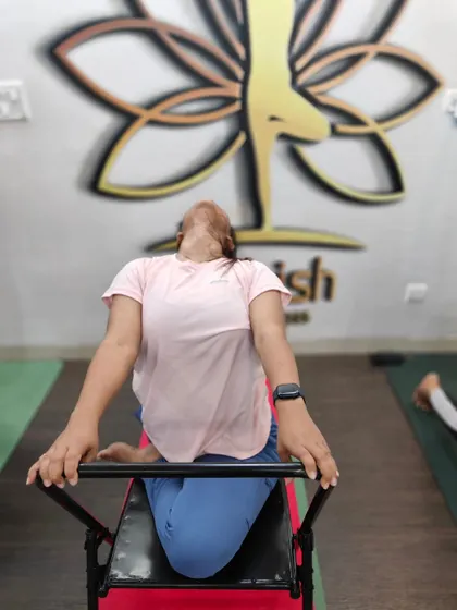 A student uses a specialized back-bending bench to safely open the thoracic spine.