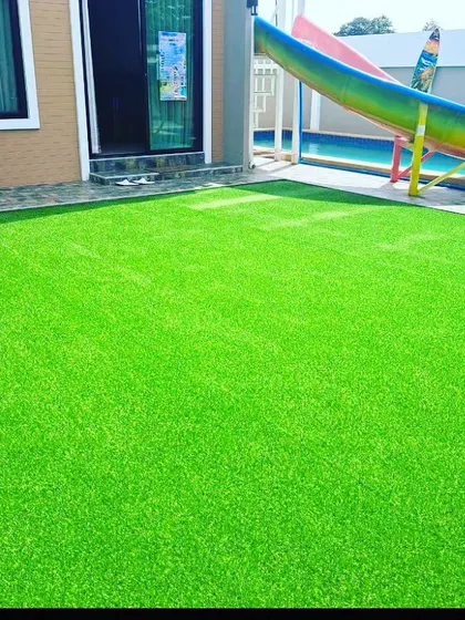 An artificial grass installation in a children's play area next to a pool. It's softer and safer than concrete for kids to play on.