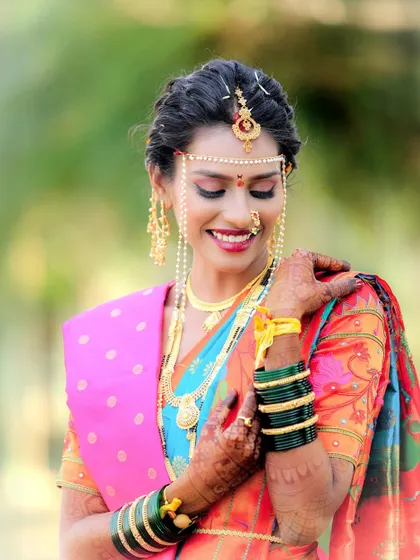 A radiant Maharashtrian bride adorned with the traditional mundavalya. Her colorful Paithani saree and joyful smile are the highlights of this beautiful outdoor portrait.