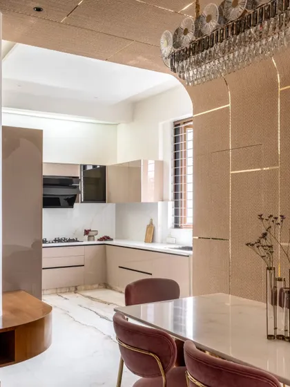 This view shows the seamless transition from the dining area to the open kitchen. The consistent flooring and color palette create a sense of unity, while architectural arches and a statement chandelier define the dining space.