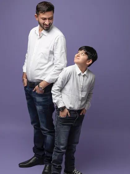 A father and son look at each other with admiration. This simple, candid pose perfectly captures the special bond they share.