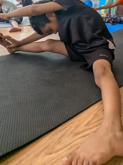 A student works on a seated side stretch during a yoga and flexibility session. We incorporate elements of yoga to improve flexibility, balance, and focus in our young athletes.
