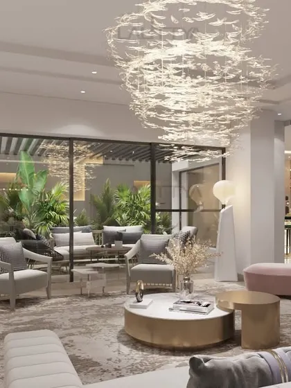 This living room is designed for both beauty and comfort. The curved blush sofa creates a cozy seating area, complemented by plush quilted benches and elegant armchairs. Sculptural side tables and layered textures bring depth to the space.