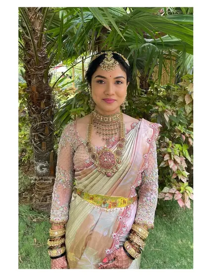 Drutha's complete wedding look. The soft pastel colors of her saree and the intricate gold jewelry are tied together with a flawless makeup application that lasts all day.