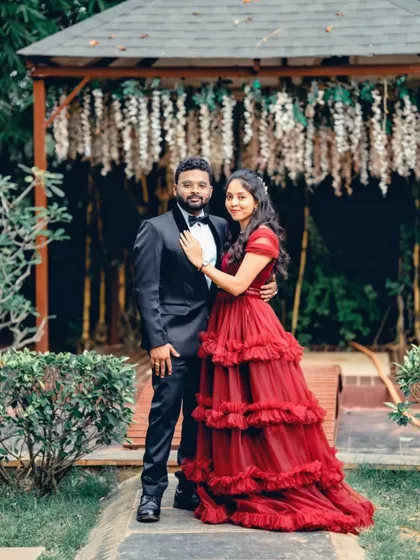 Posing together, this couple showcases a classic pre-wedding look. The deep maroon of her gown and the black of his tuxedo create a rich and elegant color palette.