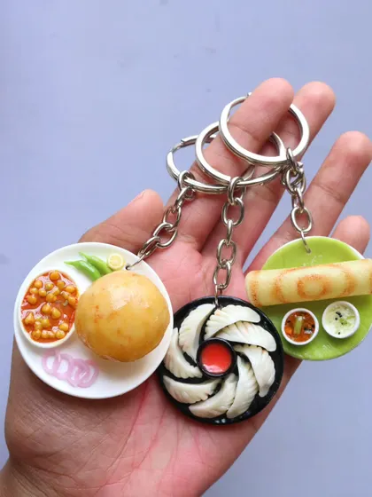 A set of three popular food keychains: chole bhature, momos, and dosa.