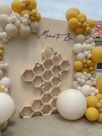 A "Mama to Bee" baby shower theme, featuring a neutral color palette with pops of yellow. The honeycomb shelf is a unique and functional piece, perfect for displaying small favors or decor.