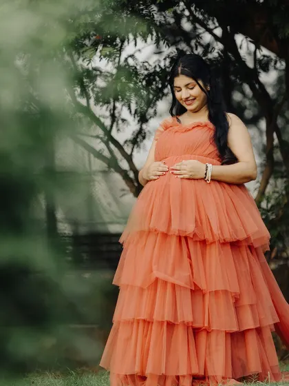 A lovely solo portrait of the mother-to-be, cradling her baby bump in our soft peach tulle gown. A perfect, comfortable, and beautiful rental choice.