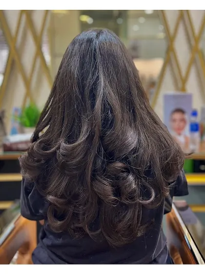 This is another example of a beautiful layer cut on long hair, styled with soft curls to enhance the texture and movement of the layers.