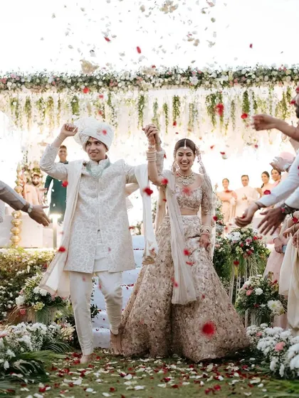 A grand exit from the ceremony. The couple is showered with petals, and the bride's makeup remains flawless and radiant.