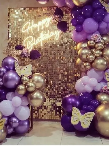 A luxurious gold and purple butterfly-themed decoration with a gold sequin wall and a "Happy Birthday" neon sign.