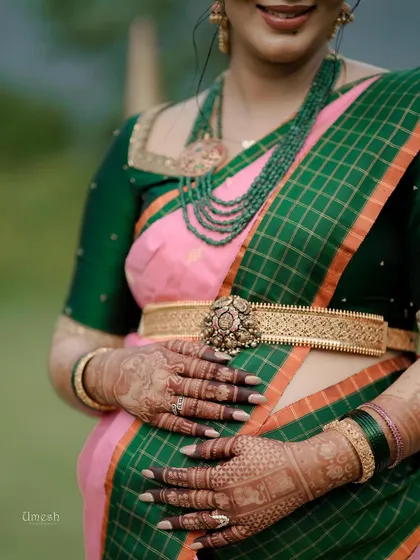 A detailed view of the silver oddiyanam and the layered green bead necklace, a popular choice for baby shower ceremonies.